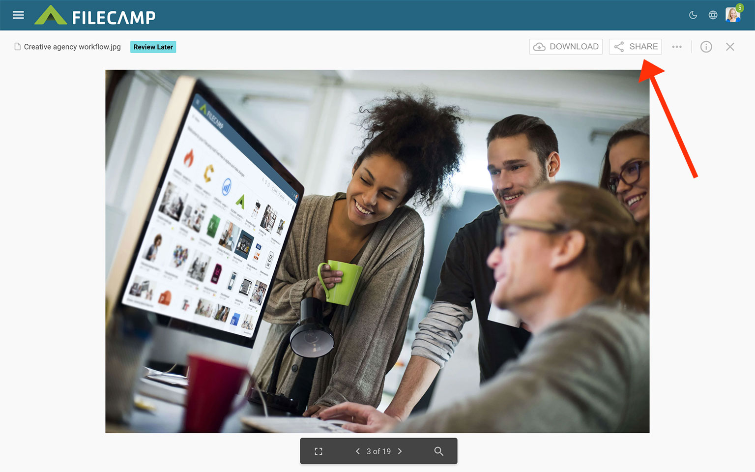 Group of young professionals collaborating around a computer in an office.